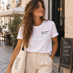 Mulher com T-shirt branca bordada com a frase “Mais vale late que never” da Poesia Cocó