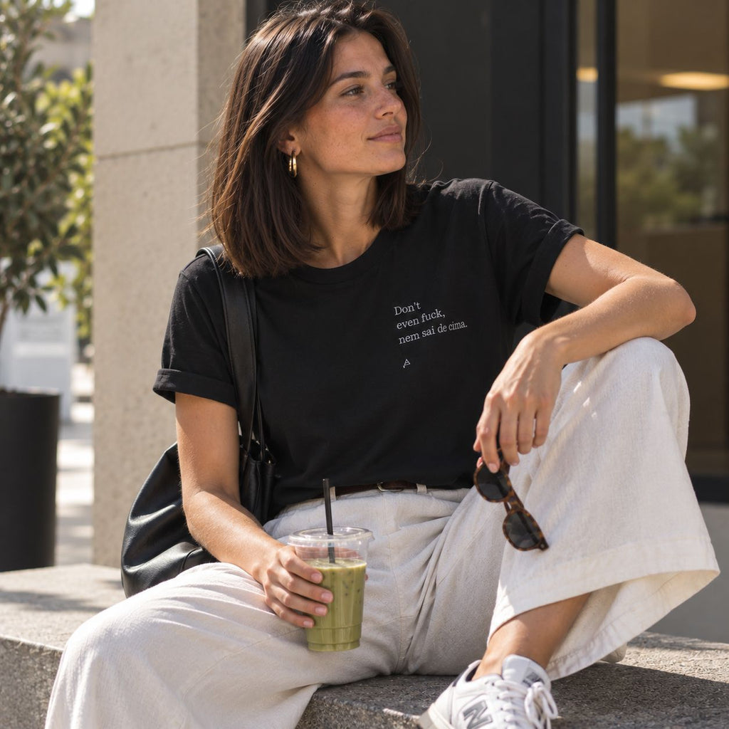 Mulher com T-shirt preta bordada com a frase “Don’t even fuck nem sai de cima” da Poesia Cocó