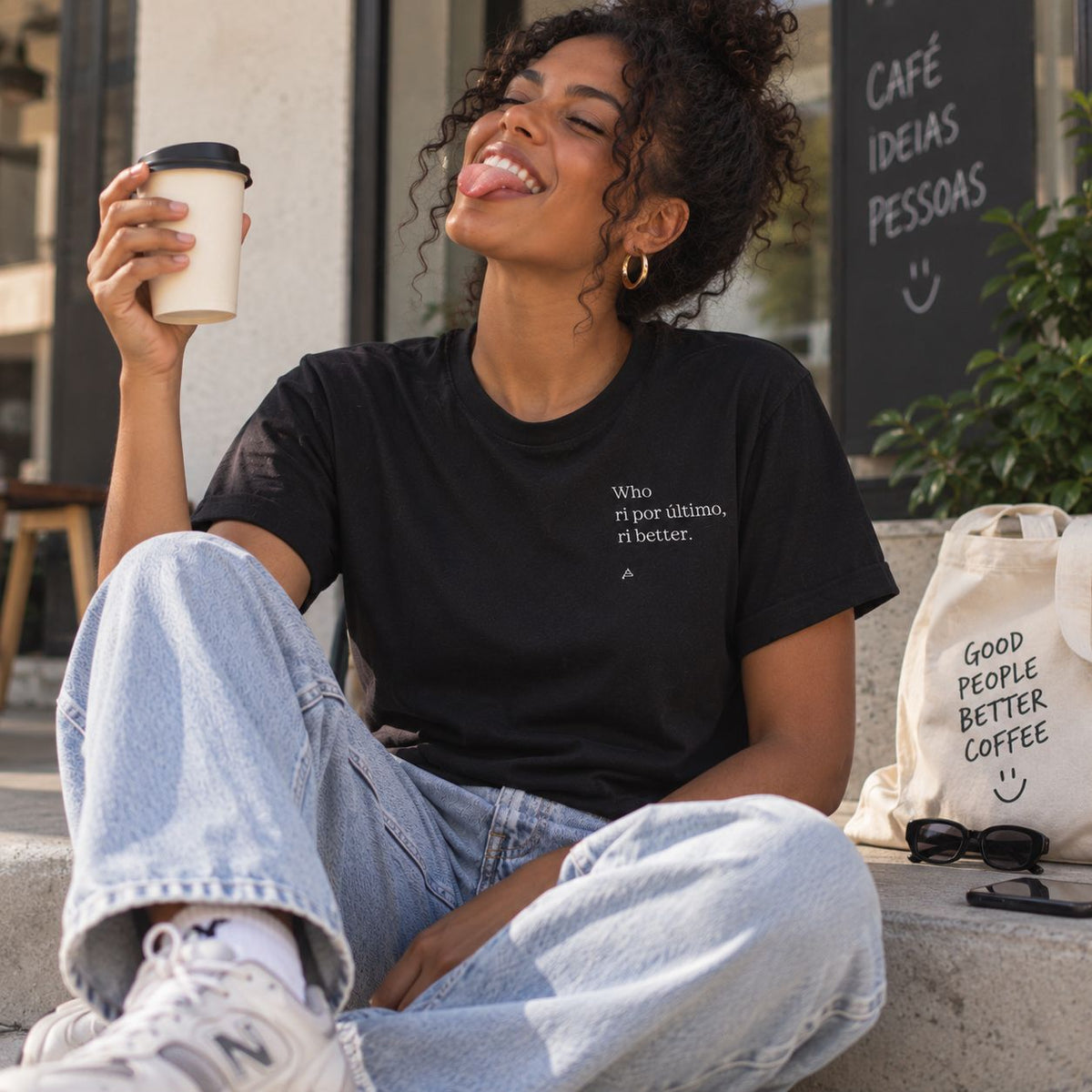 Mulher com T-shirt preta bordada com a frase “Who ri por último, ri better” da Poesia Cocó