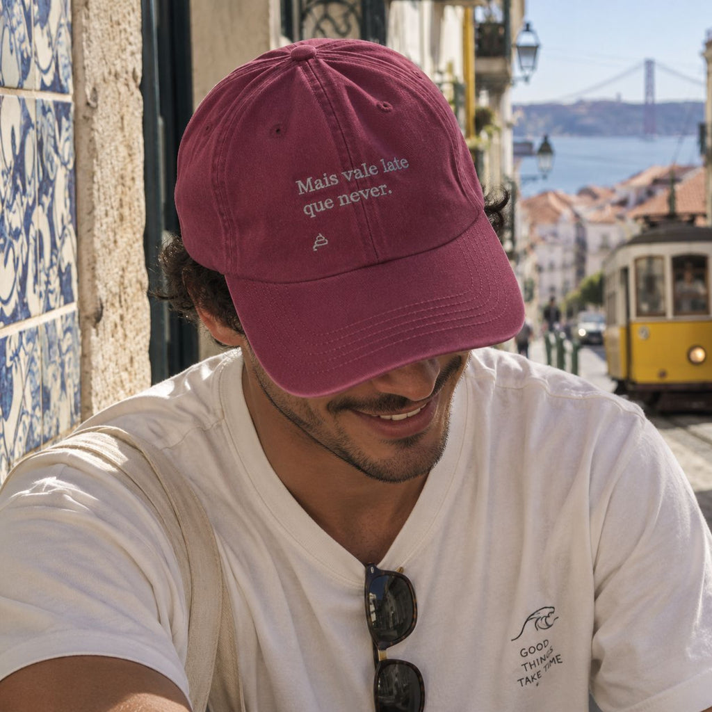Homem com boné bordô bordado “Mais vale late que never.” da Poesia Cocó