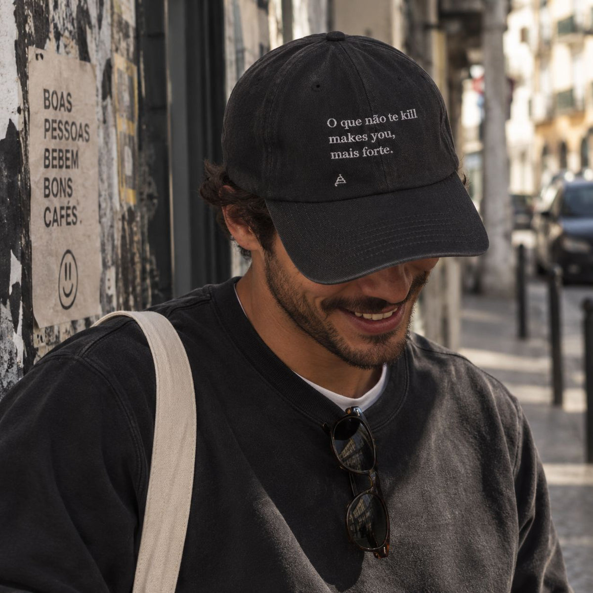 Homem com boné preto bordado “O que não te kill makes you mais forte.” da Poesia Cocó