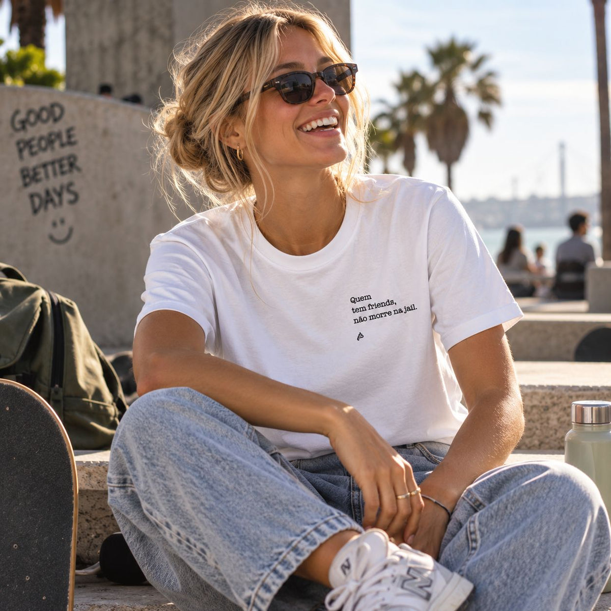 Mulher com T-shirt branca bordada com a frase “Quem tem friends não morre na jail” da Poesia Cocó