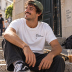 Homem com T-shirt branca bordada com a frase “Quem tem friends não morre na jail” da Poesia Cocó