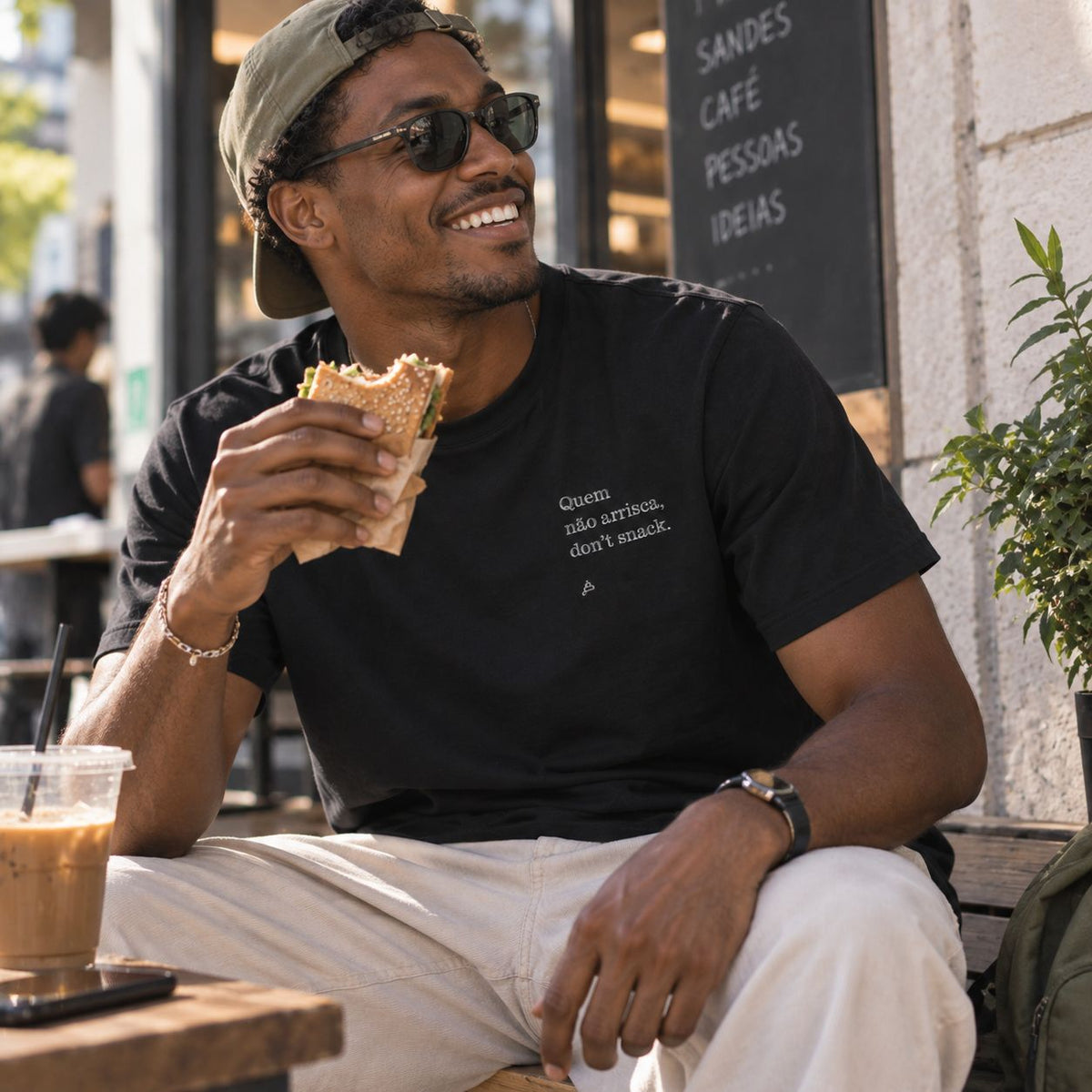 Homem com T-shirt preta bordada com a frase “Quem não arrisca, don’t snack” da Poesia Cocó