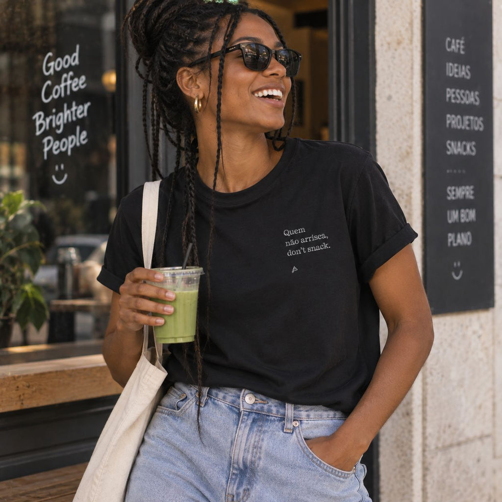 Mulher com T-shirt preta bordada com a frase “Quem não arrisca, don’t snack” da Poesia Cocó