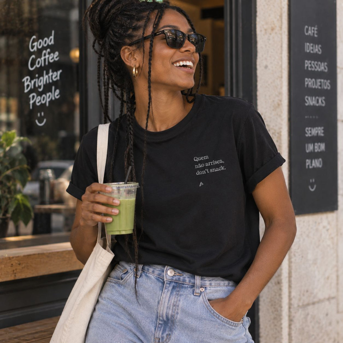Mulher com T-shirt preta bordada com a frase “Quem não arrisca, don’t snack” da Poesia Cocó